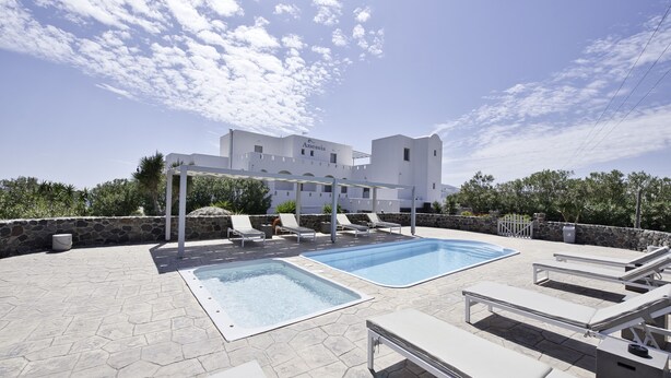 Un hotel con piscina, sillas de descanso y un muro de piedra.