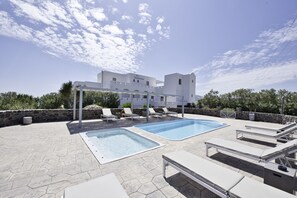 Un hotel con piscina, sillas de descanso y un muro de piedra.