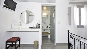 Un baño moderno con espejo, lavabo e inodoro. Hay un pequeño banco y una cesta en el suelo.