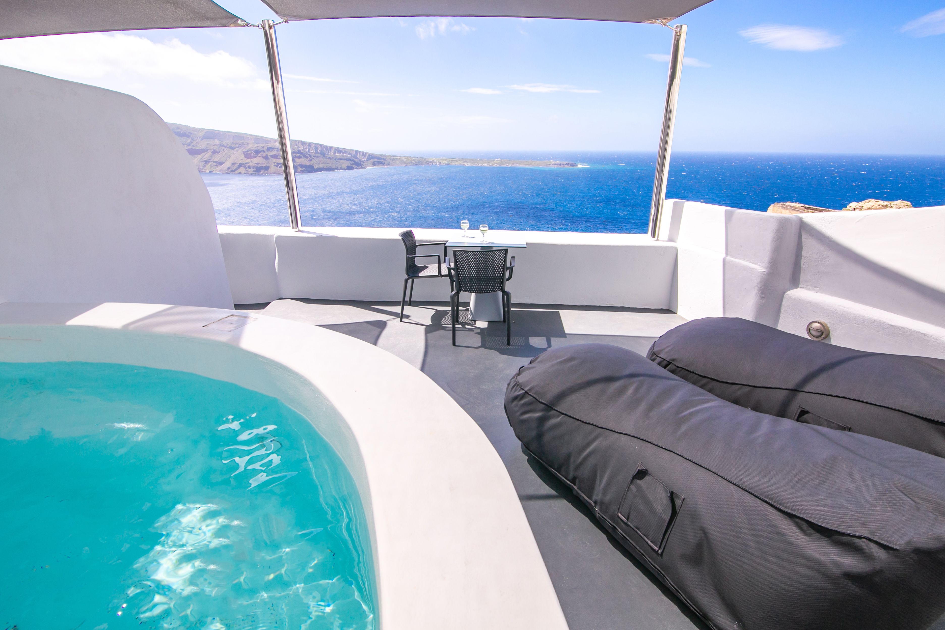 Ein Balkon mit Whirlpool, einem Tisch mit Stühlen und Blick aufs Meer.