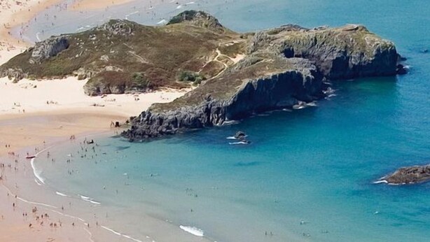 A coastal landscape with rocky outcrops, a sandy beach, and clear blue waters. - Hotel Marítimo Ris (Noja)