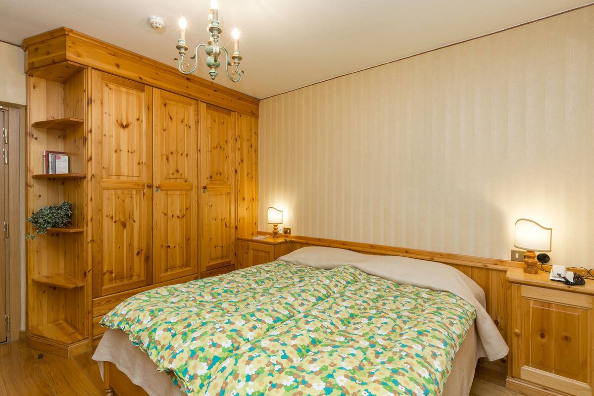 A wooden room with a bed, a nightstand, and a wardrobe.
