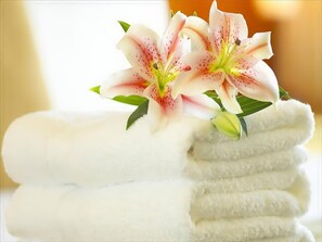 Une pile de serviettes blanches sur laquelle est posé un lys rose et blanc.