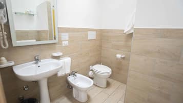 A bathroom with a sink, bidet, toilet, and a mirror.