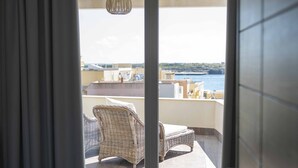 A room with a view of the sea, a wicker chair, a bed, and a door leading to an outdoor area. - Hotel Sole (Lampedusa)