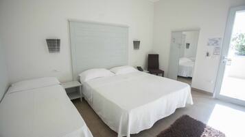 A bedroom with two beds, a large window, and a door leading to a balcony.