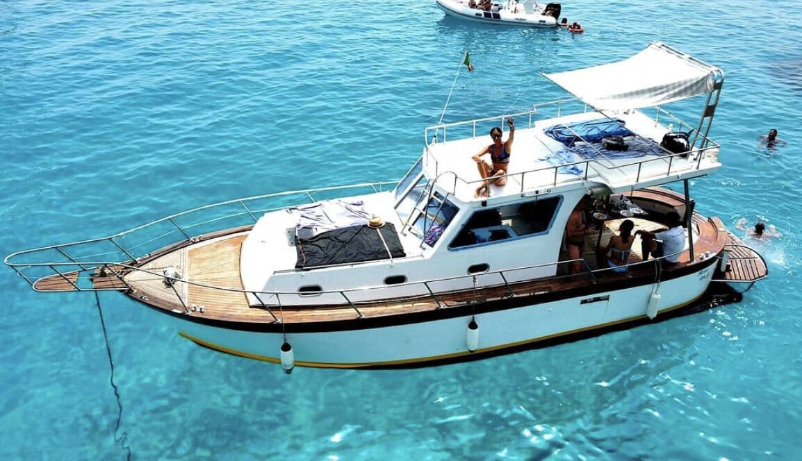 A boat with a covered deck, a cabin, and a wake behind it.