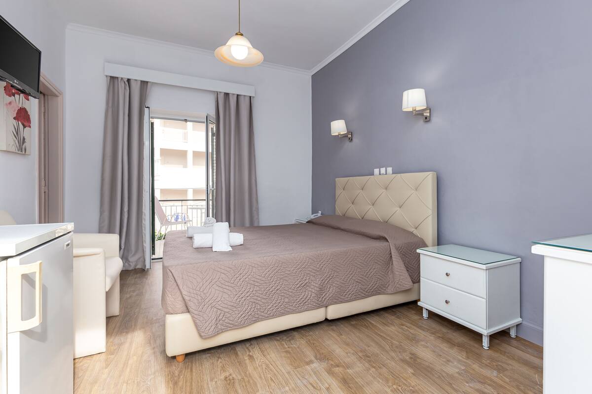 Une chambre à coucher avec un lit, des tables de chevet, un bureau, une chaise et une fenêtre avec des rideaux.