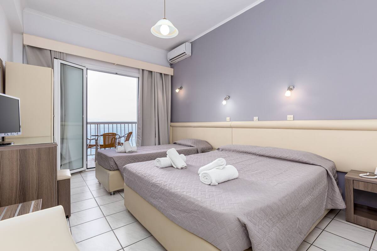 Une chambre d’hôtel avec deux lits, une télévision, un bureau et un balcon.