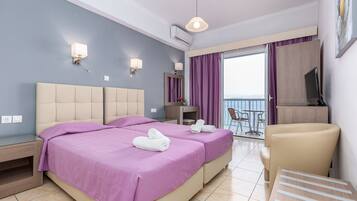 A hotel room with two beds, a desk, a chair, and a balcony with a view.