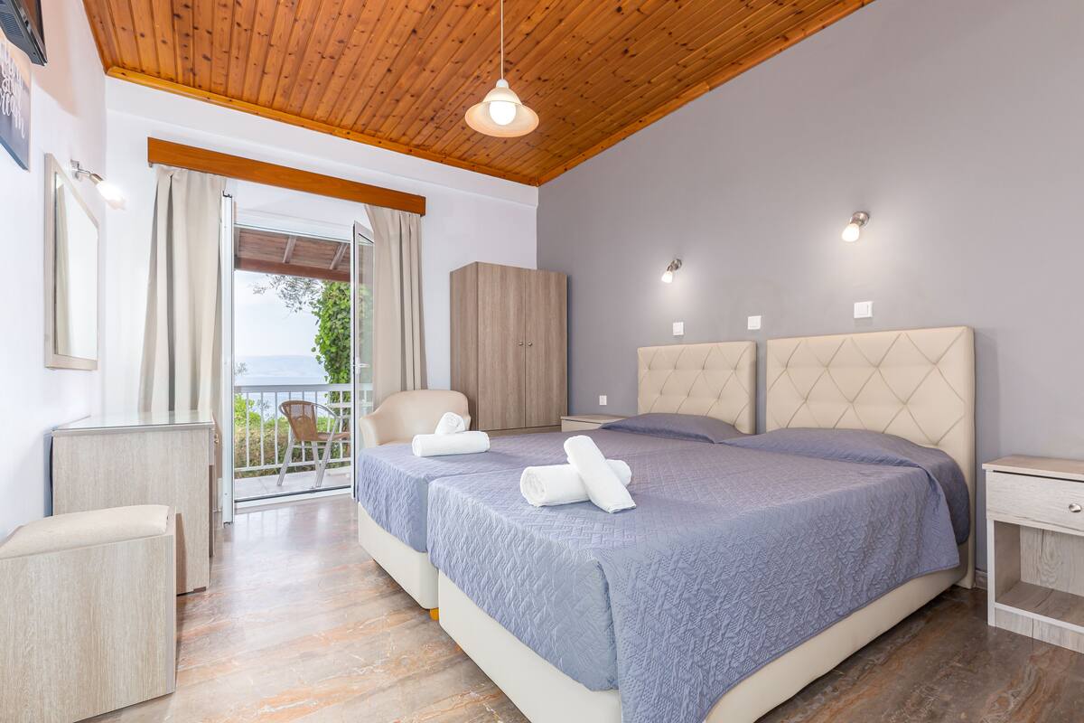 Une chambre avec deux lits, un plafond en bois et un balcon avec vue.