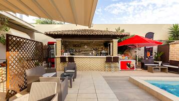 An outdoor bar area with a pool, wicker furniture, and a tiled patio.