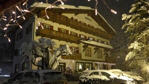 A multi-story hotel with a traditional Alpine architectural style, featuring wooden balconies and a snow-covered exterior. - Hotel Bellaria (Cortina d'Ampezzo)