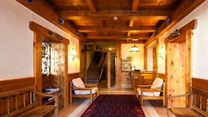 A wooden interior with a checkered floor, two wooden benches, and a staircase in the background. - Hotel Bellaria (Cortina d'Ampezzo)