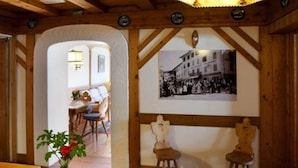 A wooden interior with a dining area, a wall-mounted photo, and a vase with flowers. - Hotel Bellaria (Cortina d'Ampezzo)