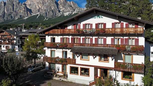 A hotel with a white facade, wooden balconies, and a mountain backdrop. - Hotel Bellaria (Cortina d'Ampezzo)