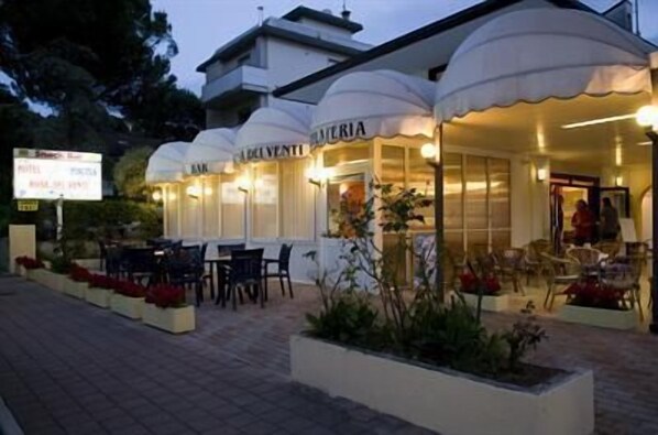 A hotel exterior with outdoor seating and a sign indicating it is a restaurant. - Rosa dei Venti (Lignano Sabbiadoro)