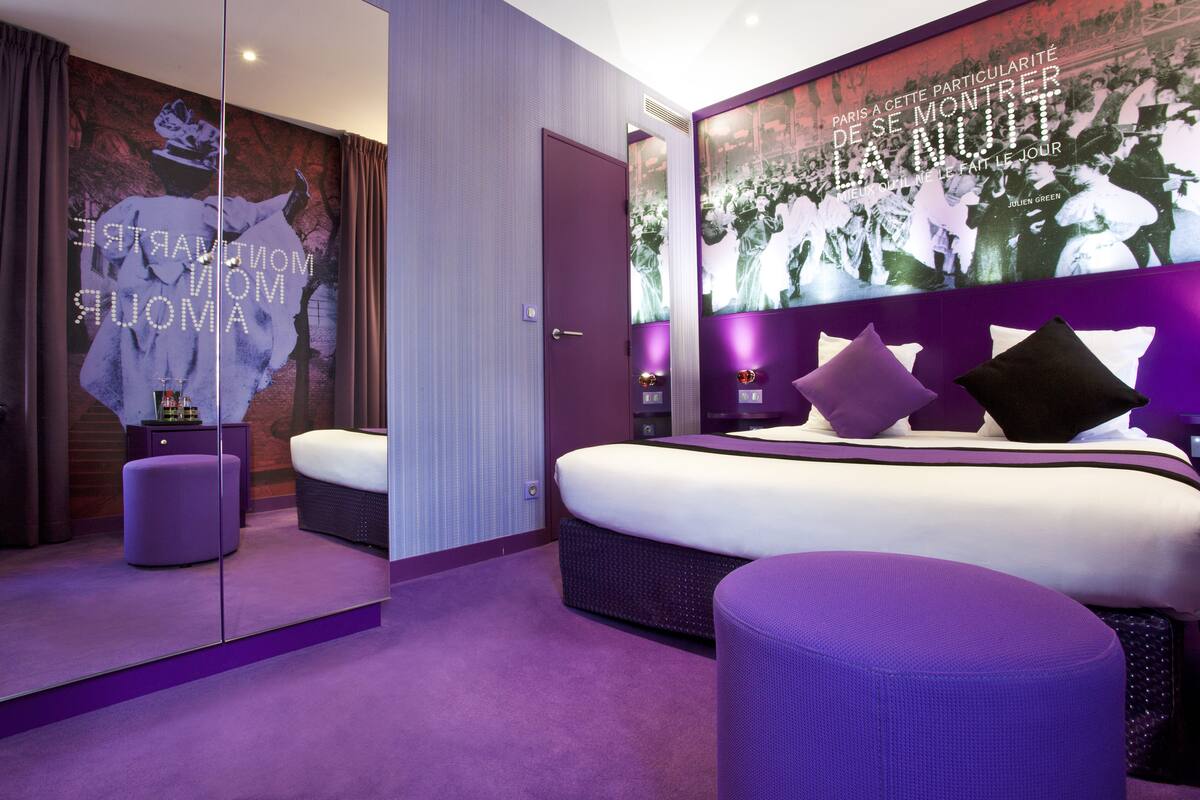 A modern bedroom with a large bed, a mirror, and a wall with a poster.