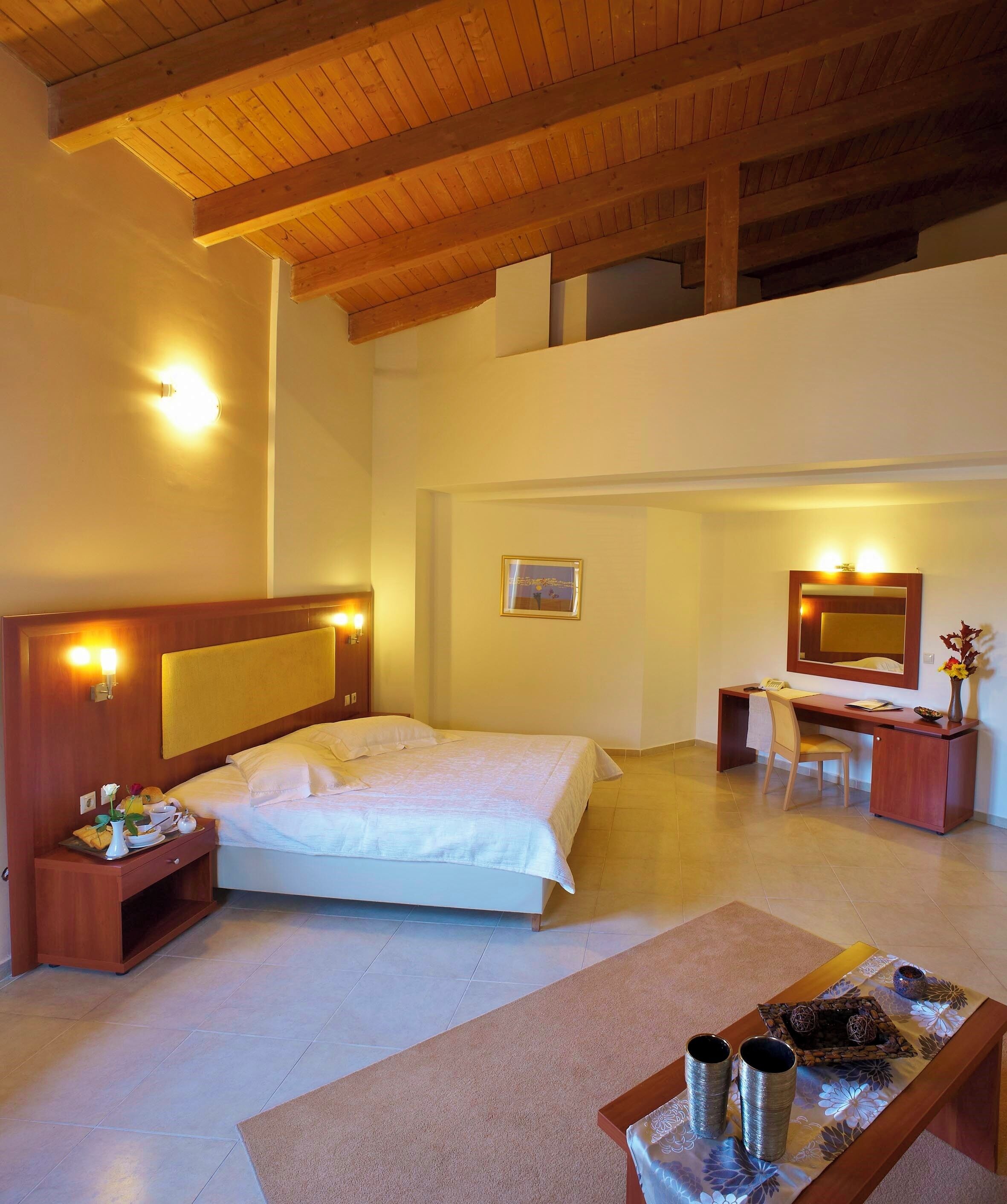 A bedroom with a bed, bedside table, desk, chair, and a mirror.