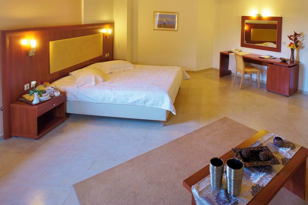Quarto com cama, mesa de cabeceira, escrivaninha, cadeira e espelho.