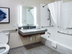 Un baño moderno con lavamanos, espejo, inodoro y bañera.