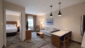 Una habitación de hotel con cama, sofá, mesa de comedor, televisor y refrigerador.