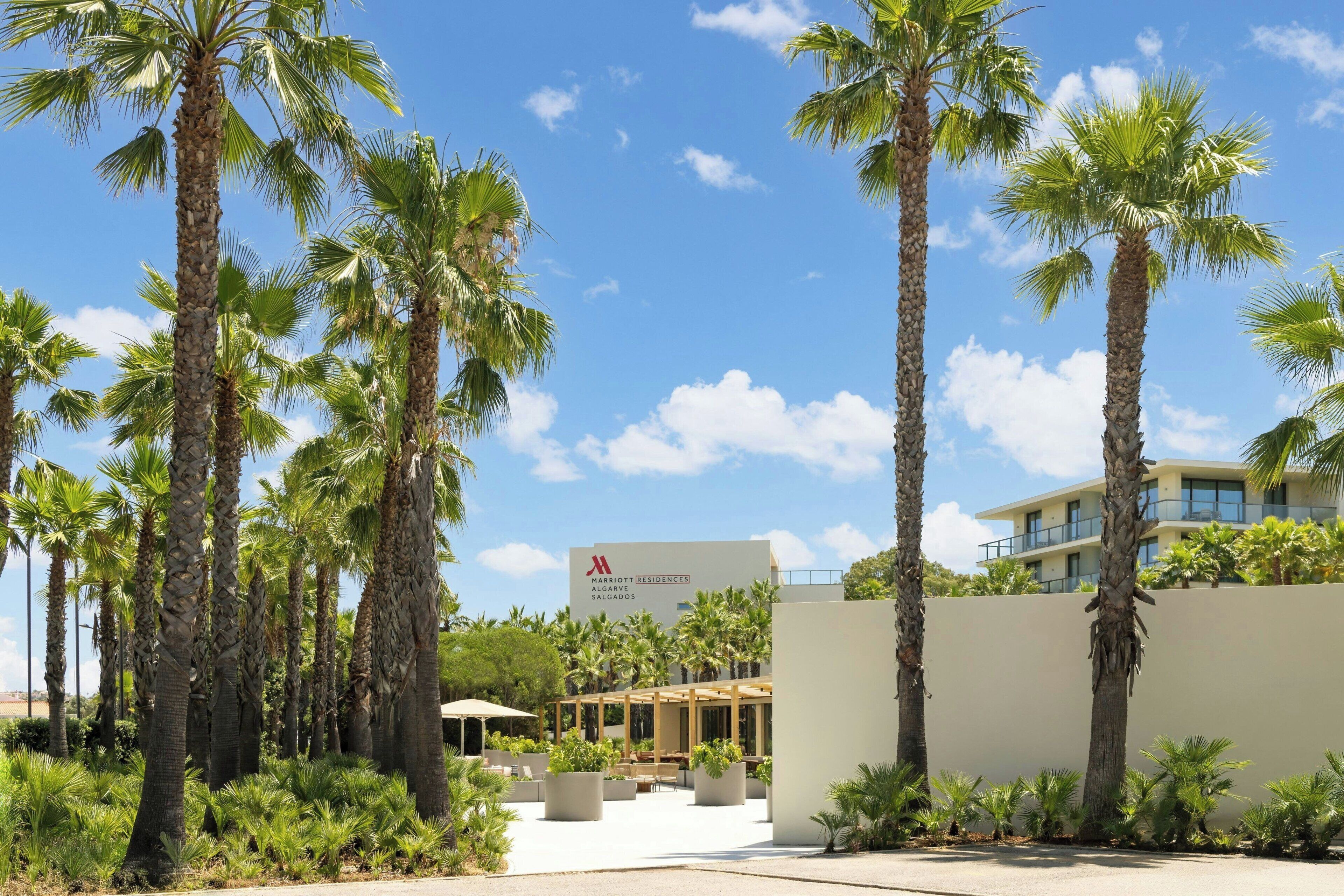 A resort with palm trees, a sign for Marriott Residences, and a modern building.