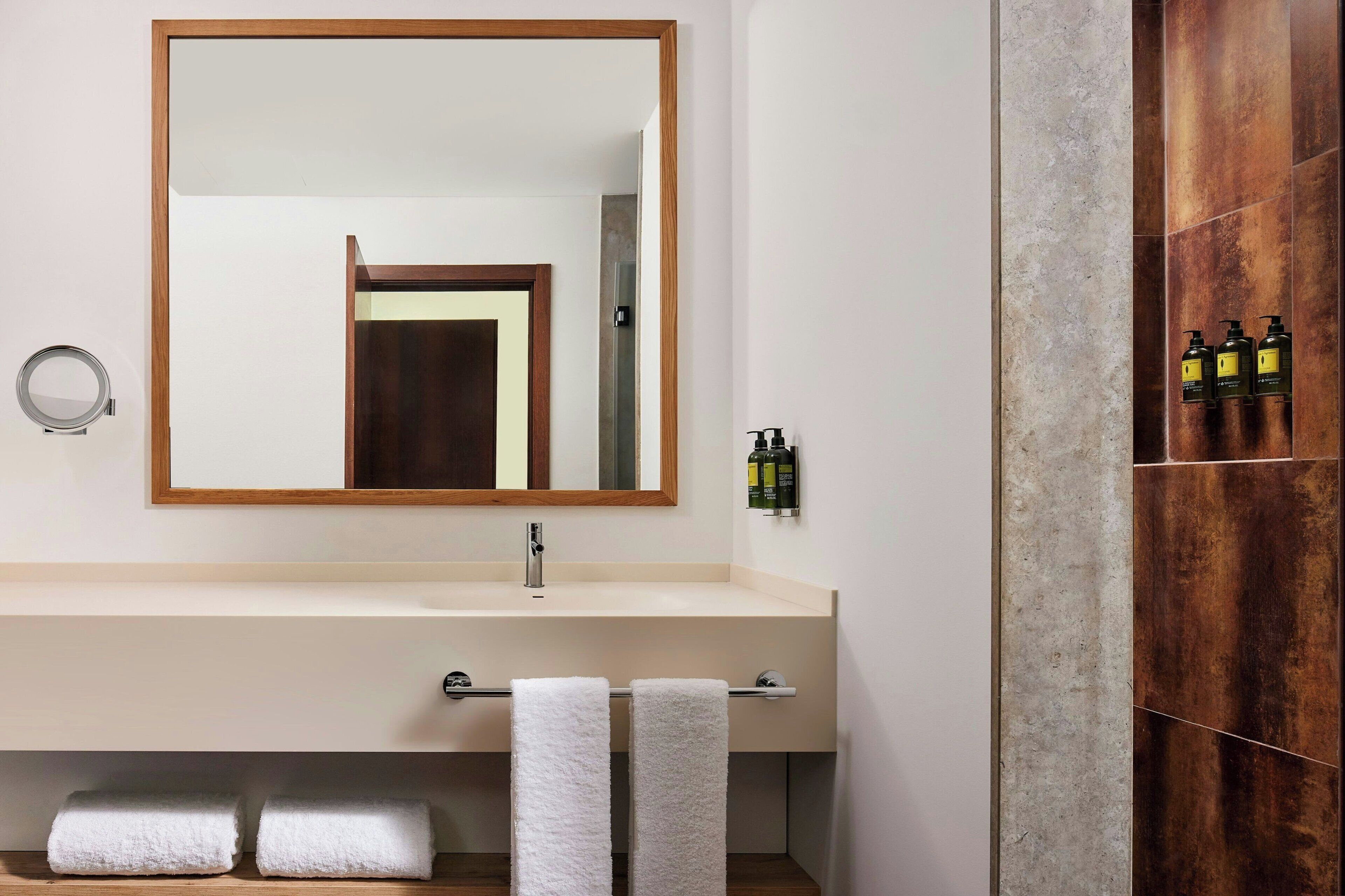 Een badkamer met een grote spiegel, een wastafel en een douchecabine van hout.