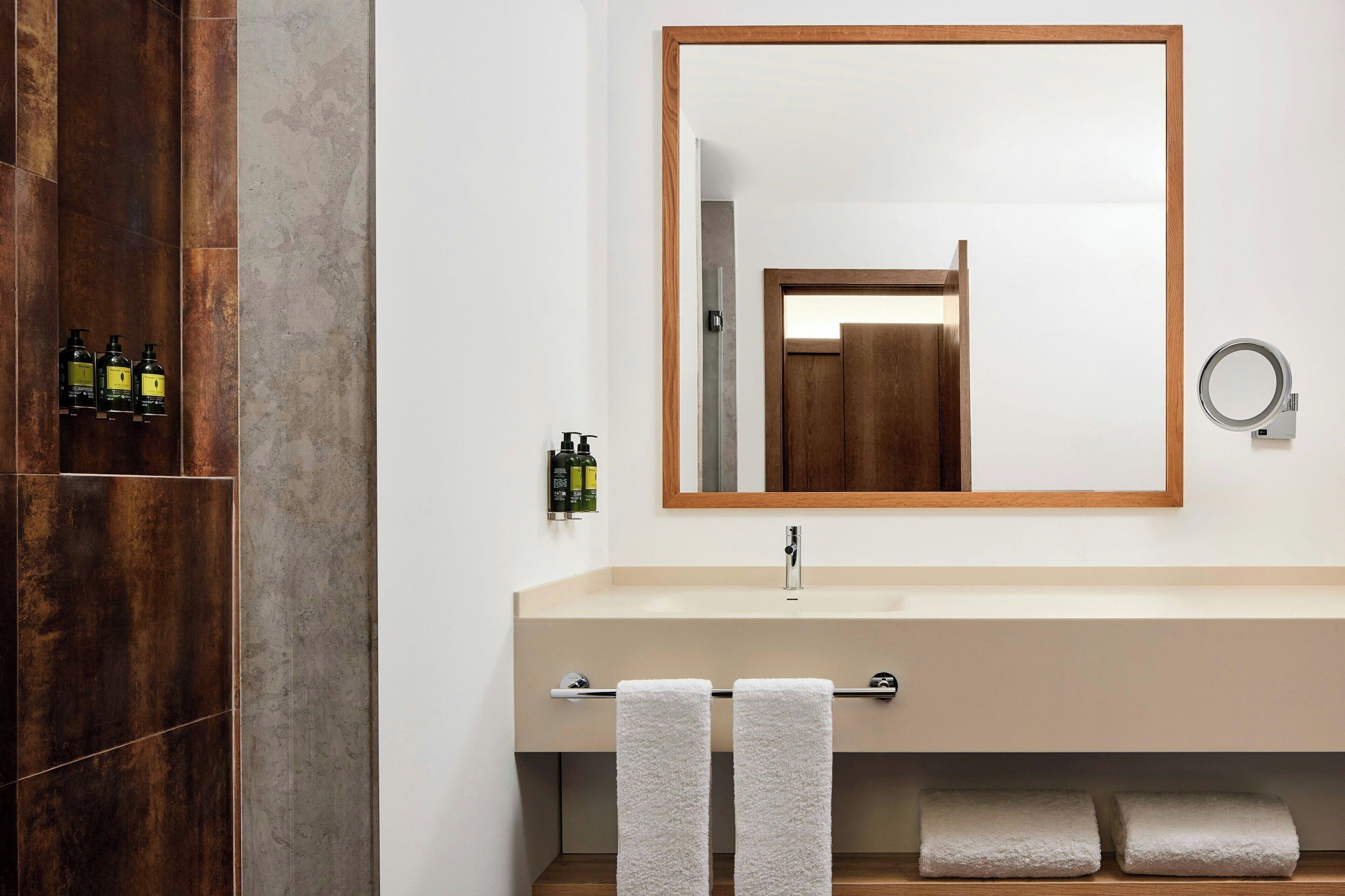 Een moderne badkamer met een houten wastafelmeubel, een grote spiegel en een handdoekrek.