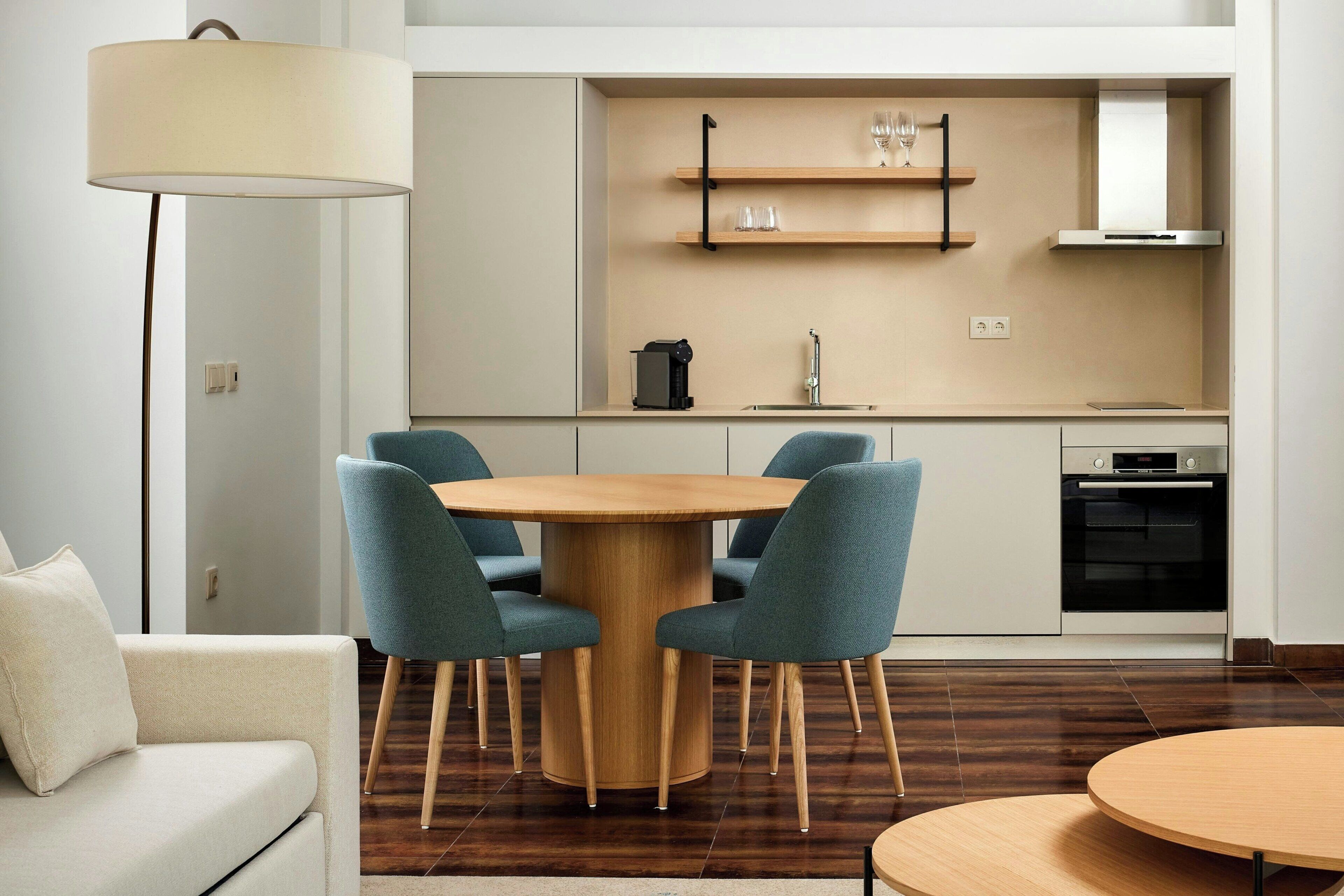 A modern kitchen with a round dining table, built-in shelves, and a built-in oven.