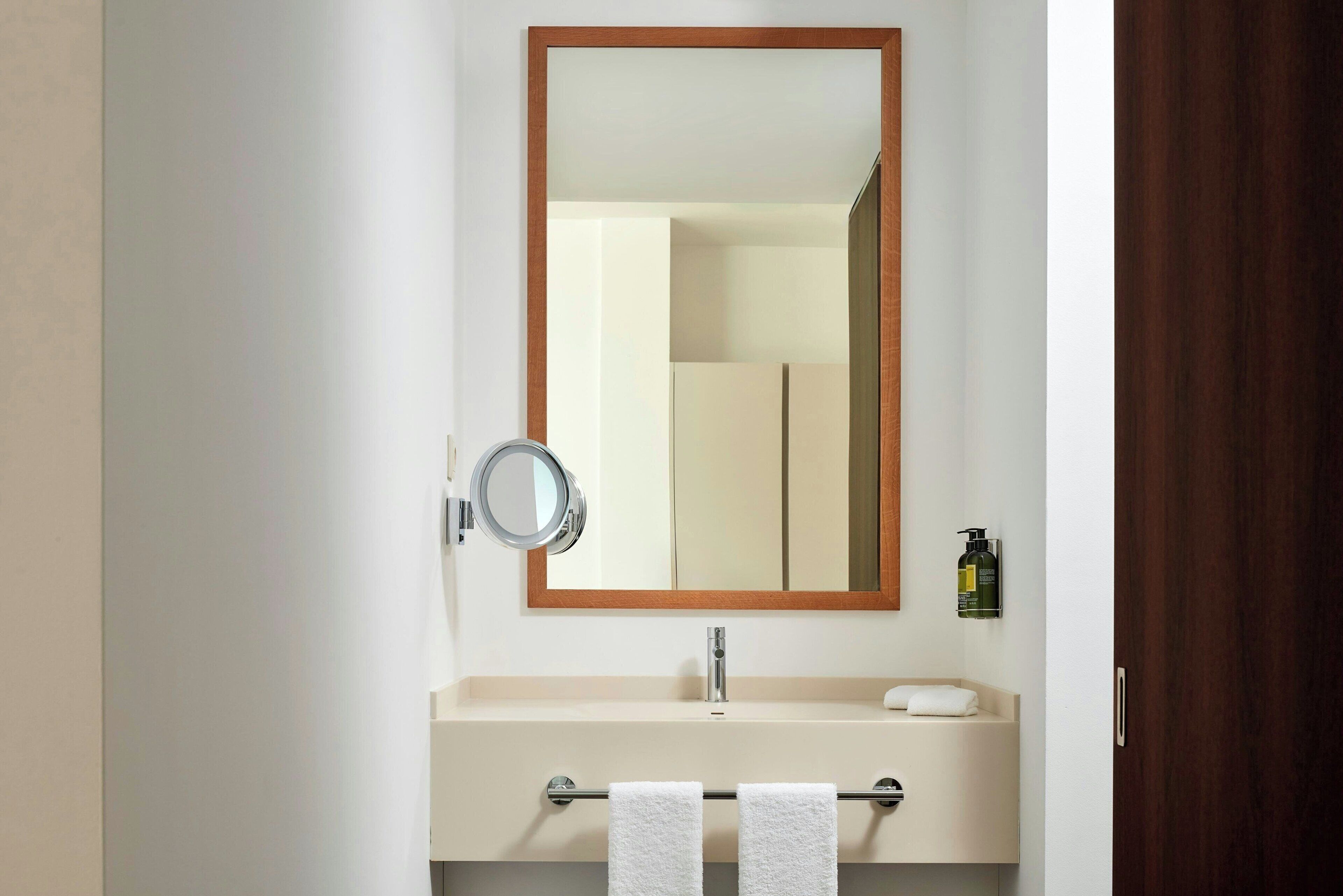A bathroom with a mirror, sink, and towel rack.