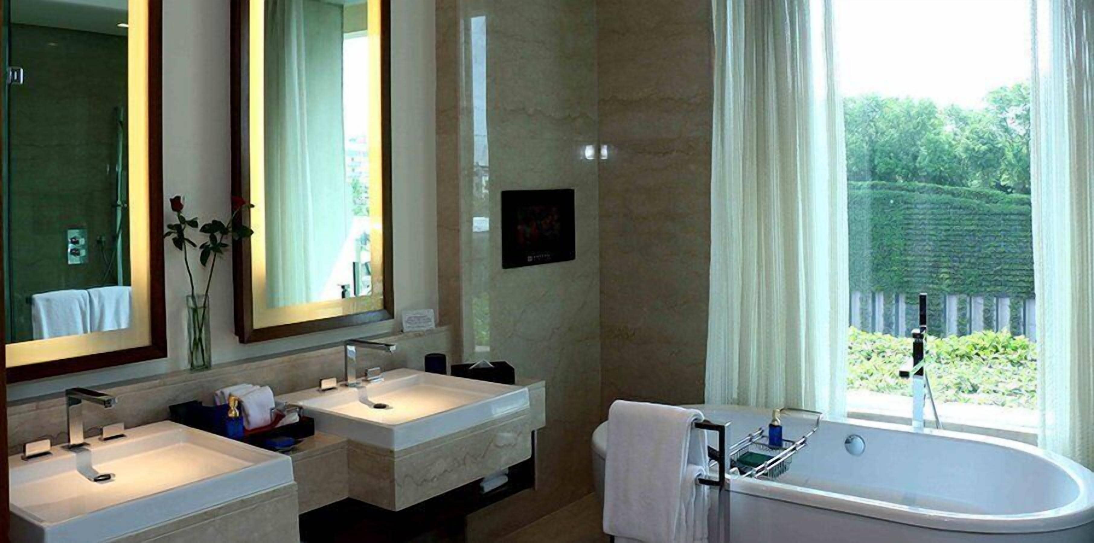 Baño con dos lavamanos, una bañera y un espejo grande.