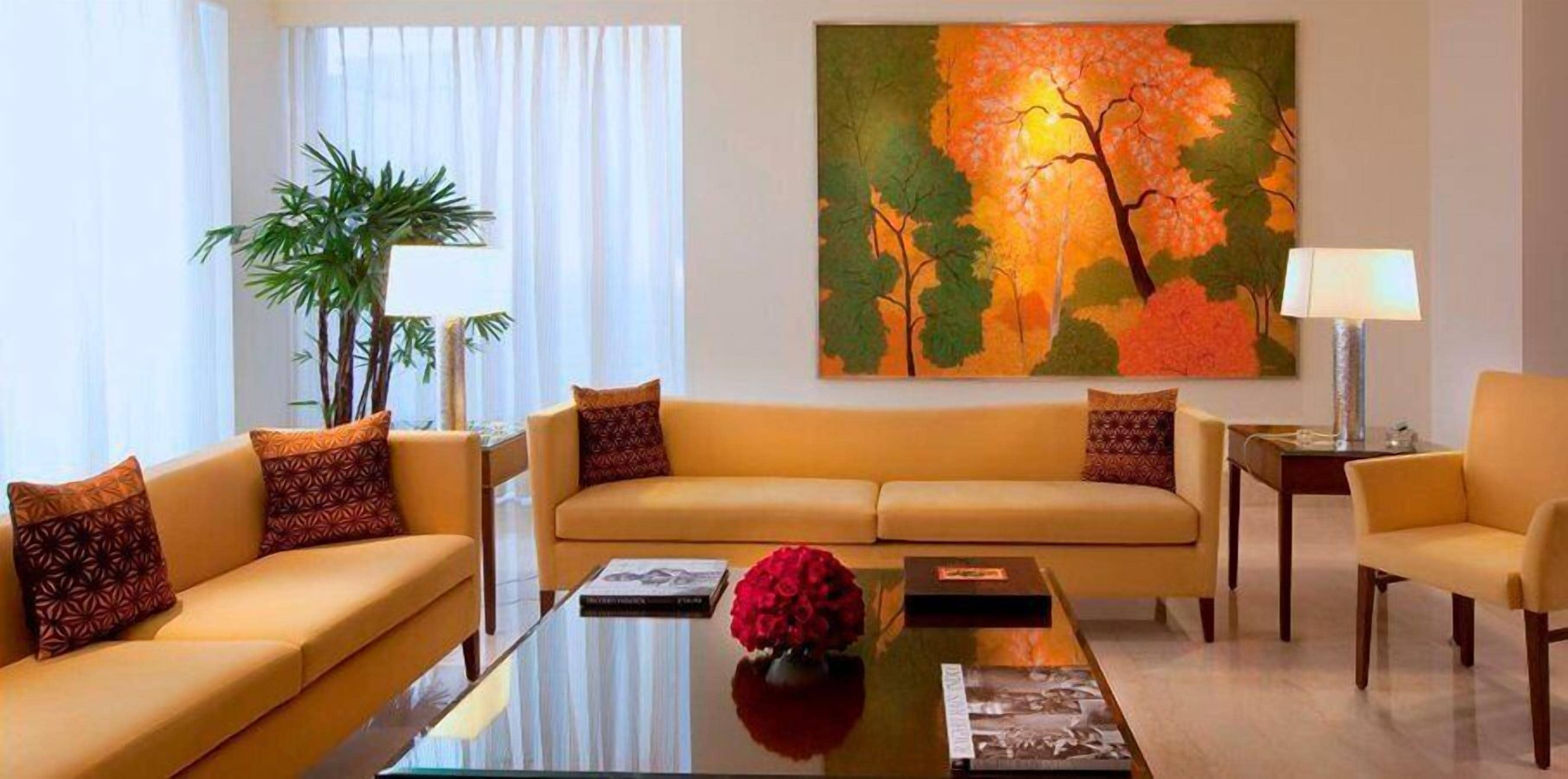 A modern living room with a sofa set, a coffee table, a painting, and a lamp.