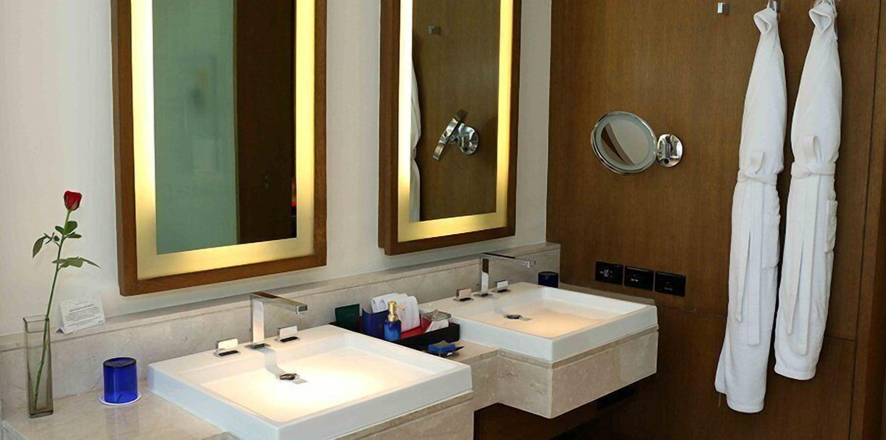 A bathroom with two sinks, a large mirror, and a towel rack with towels.