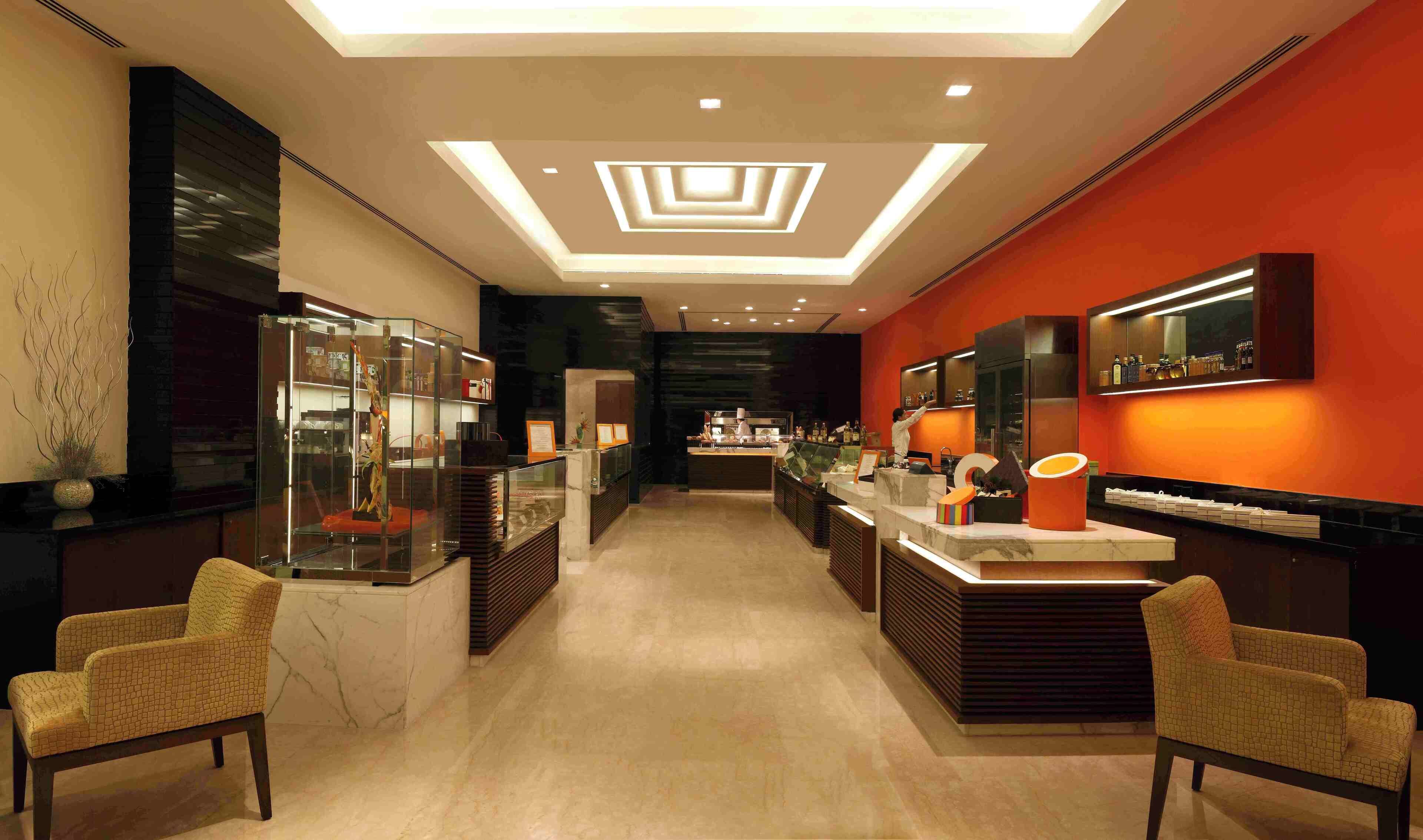 A modern hotel lobby with a central reception desk, seating areas, and a bar.