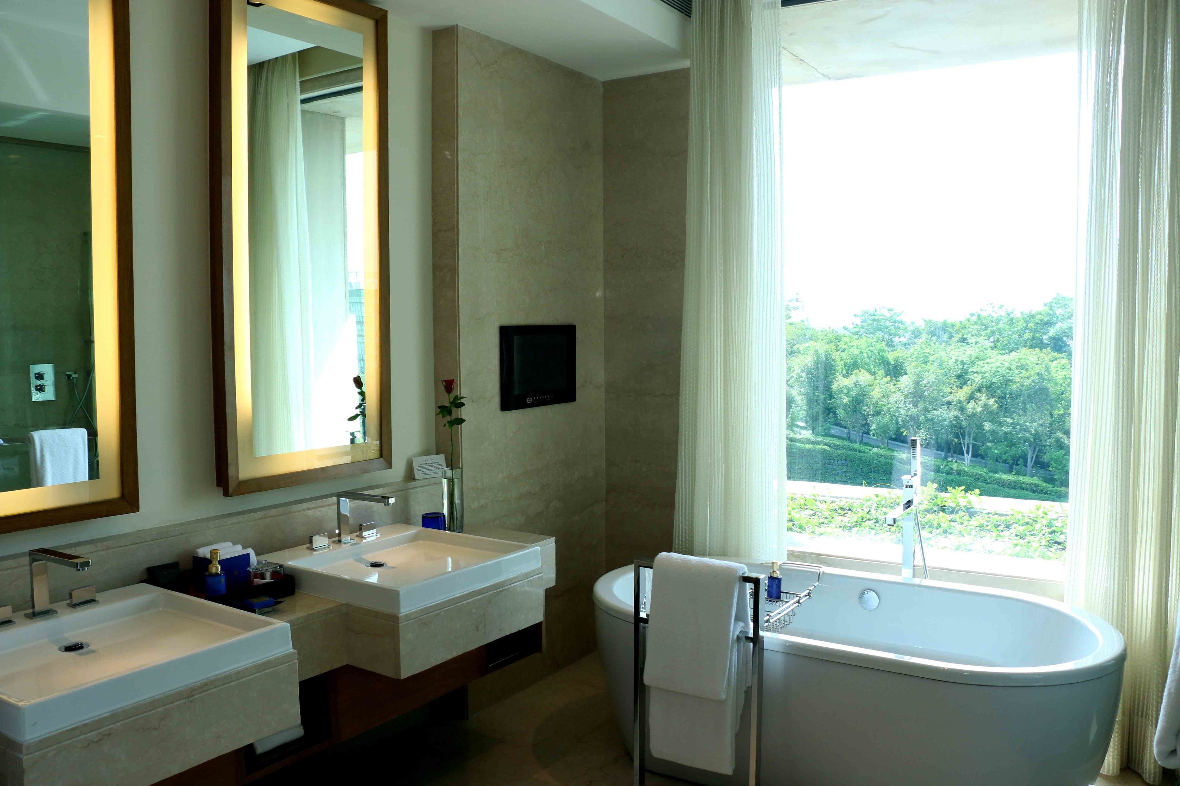 A modern bathroom with two sinks, a bathtub, and a large mirror.