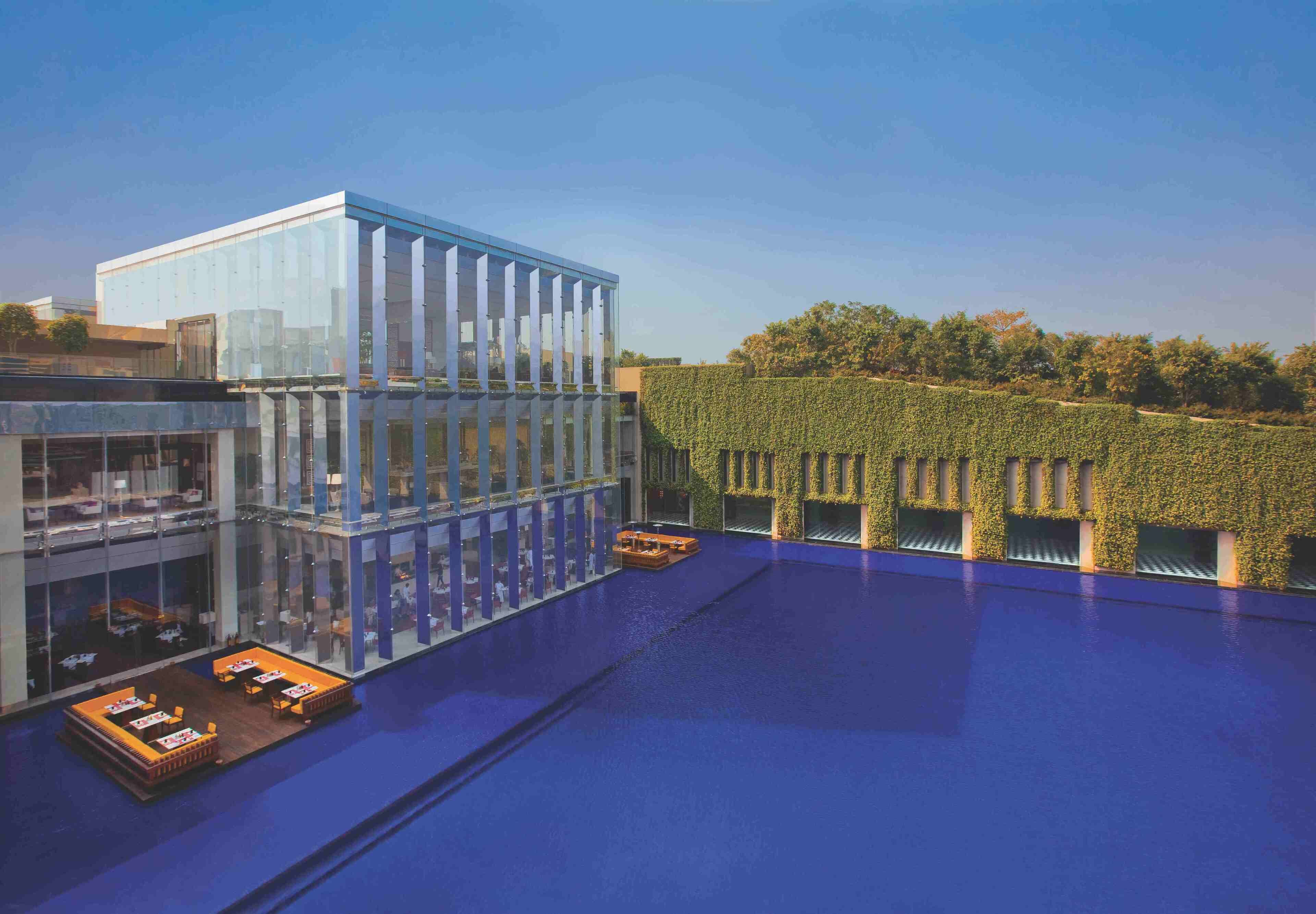 A modern building with a glass facade and a rooftop pool area.