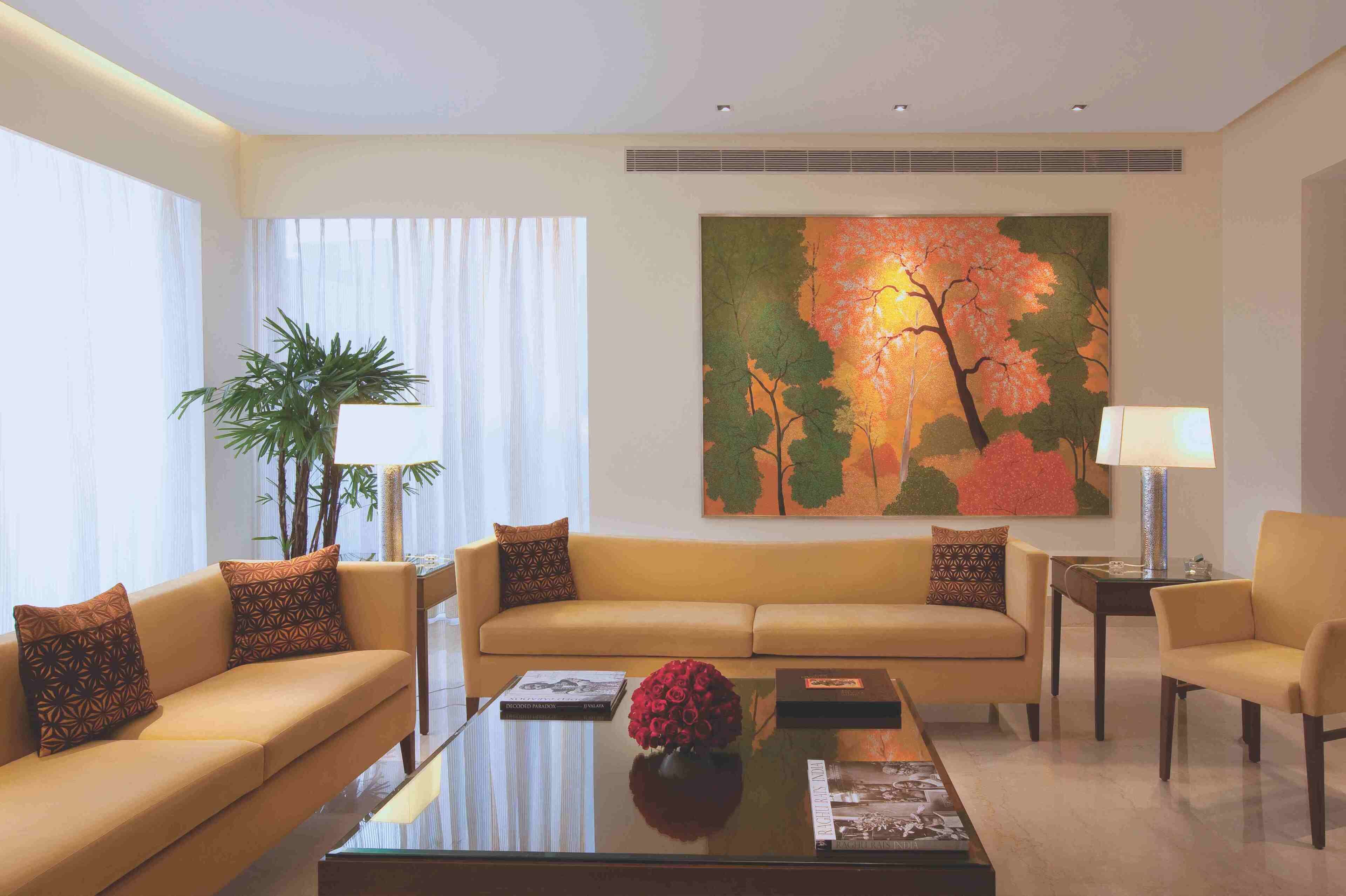 A modern living room with a sofa, armchairs, a coffee table, and a large painting.