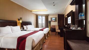 A hotel room with two beds, a desk, a chair, and a television.