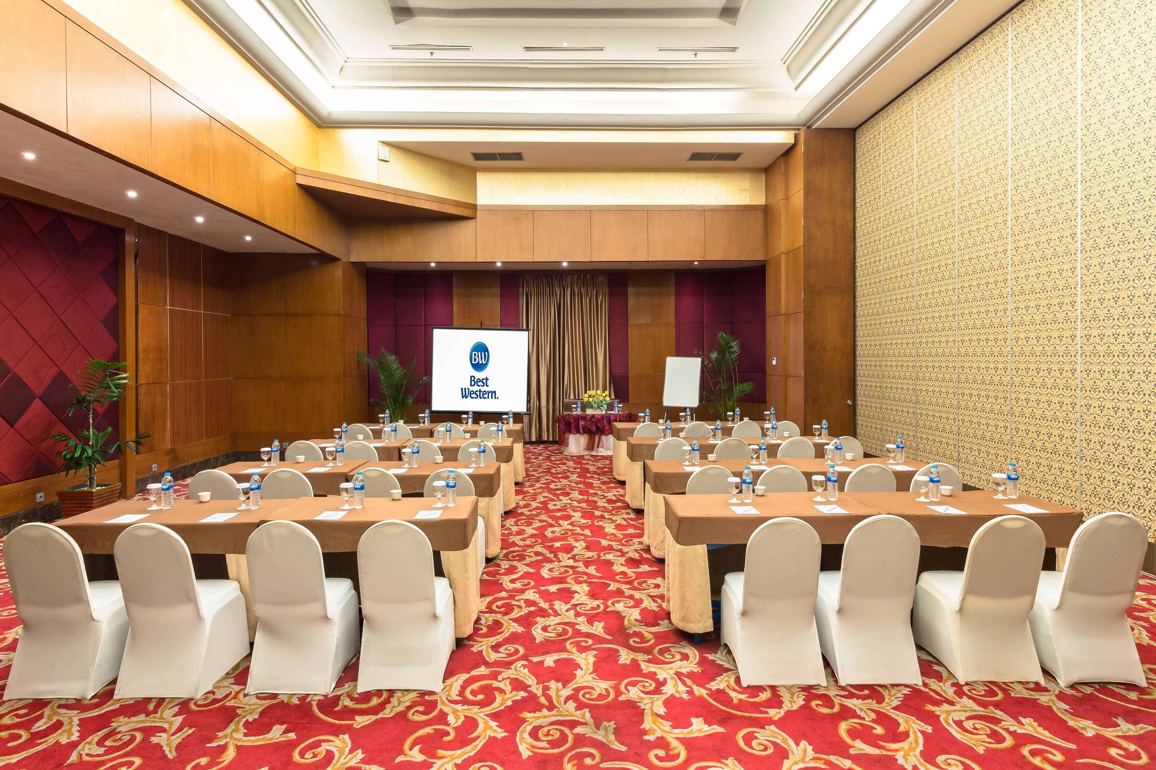 A conference room with a red carpet, white chairs, and tables set up for a meeting.