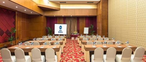 A conference room with a red carpet, white chairs, and tables set up for a meeting.