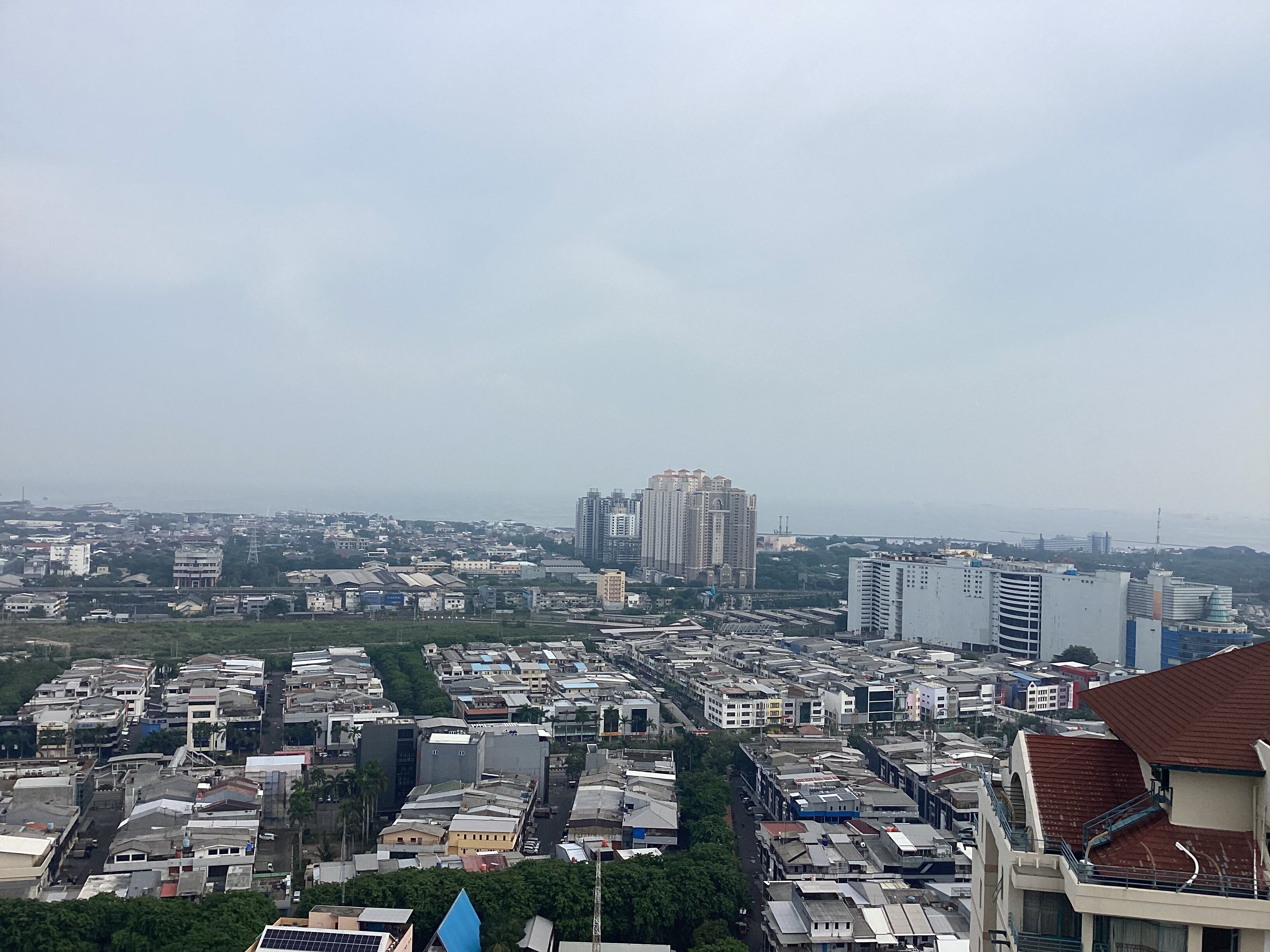 Un paisaje urbano con edificios densos, una estructura azul destacada en primer plano y una vista distante de rascacielos.