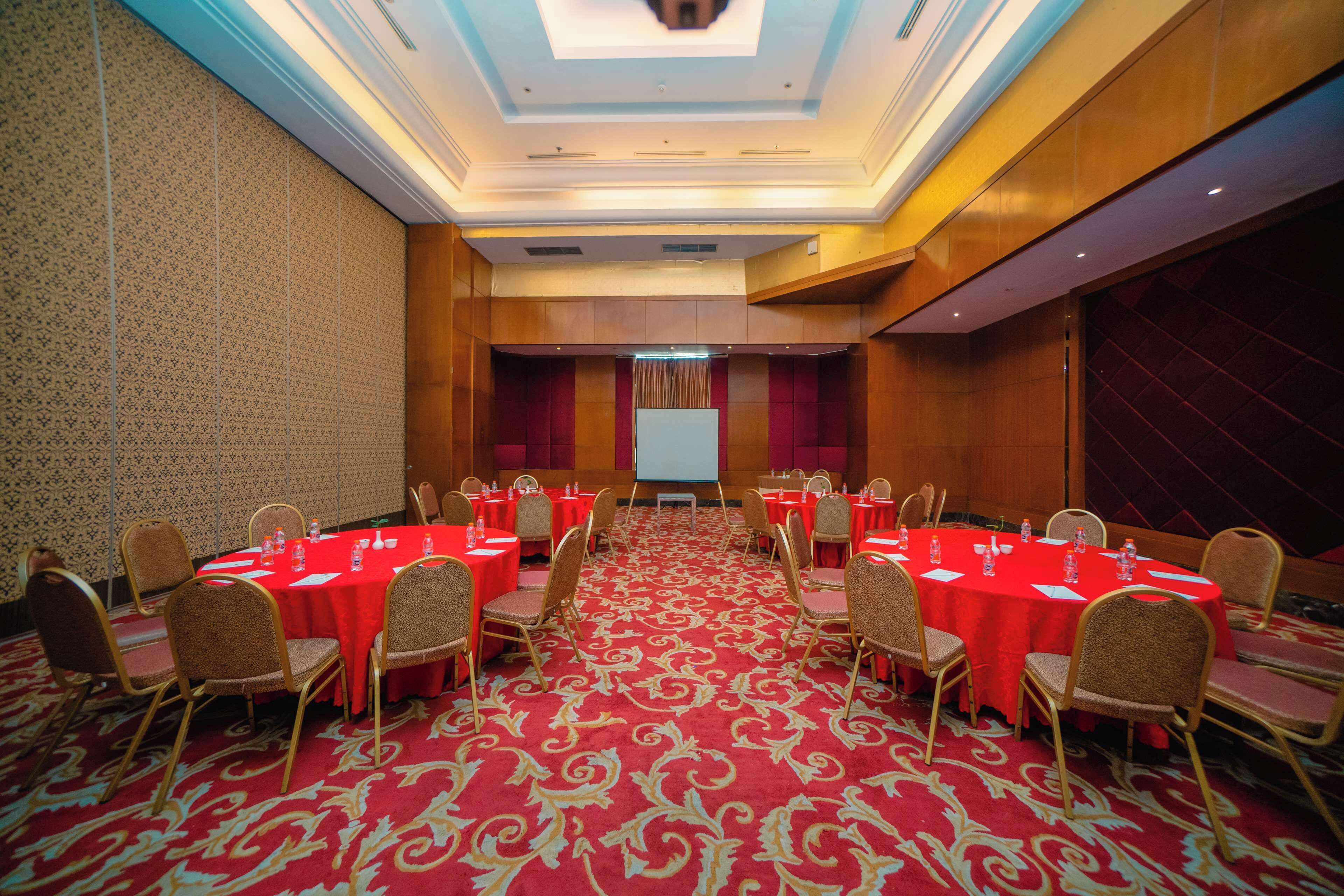 A conference room with a red carpet, gold chairs, and a projector screen at the front.