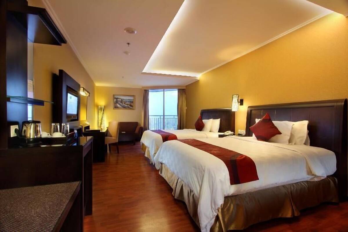 A hotel room with a large bed, a desk, a chair, and a television.