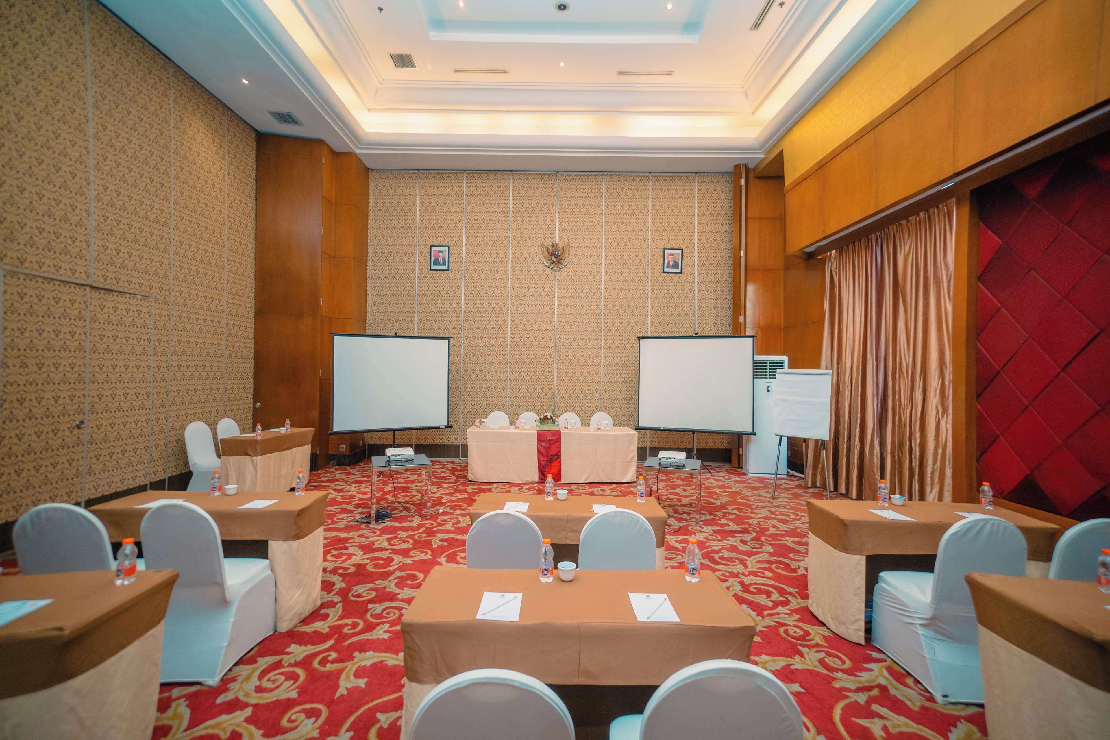 A conference room with a red carpet, white chairs, and tables set up for meetings.
