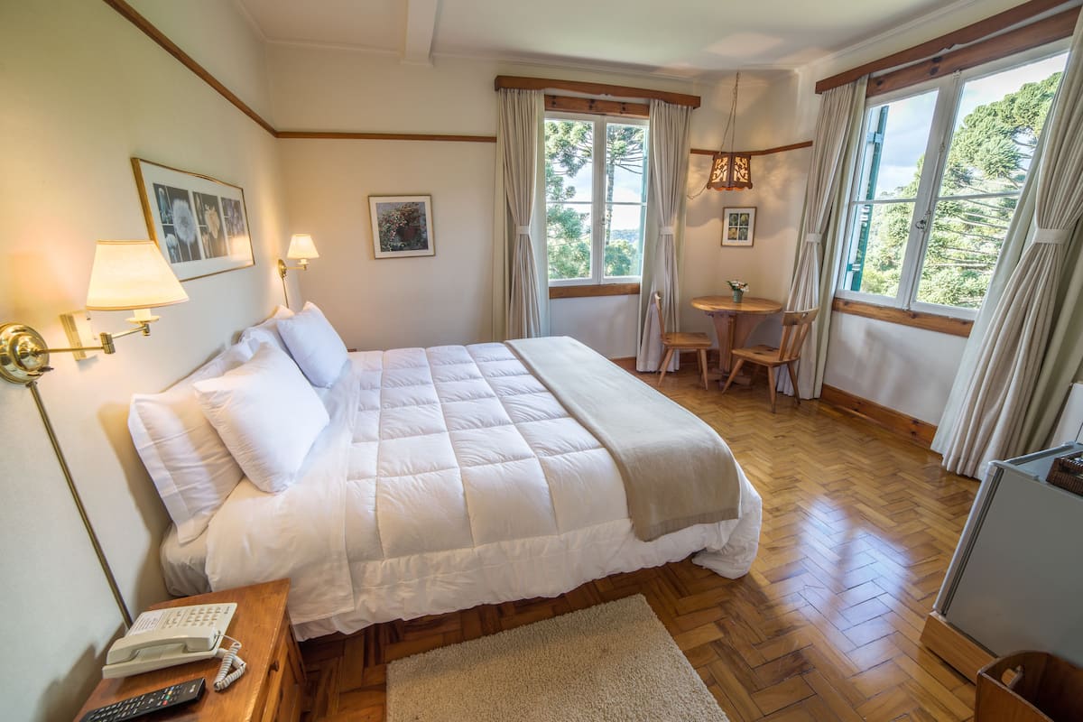 Une chambre bien rangée, avec un grand lit, des lampes de chevet, une petite table et une chaise.