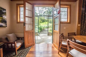 Quarto com estrutura de madeira e vista para um jardim através de portas abertas.