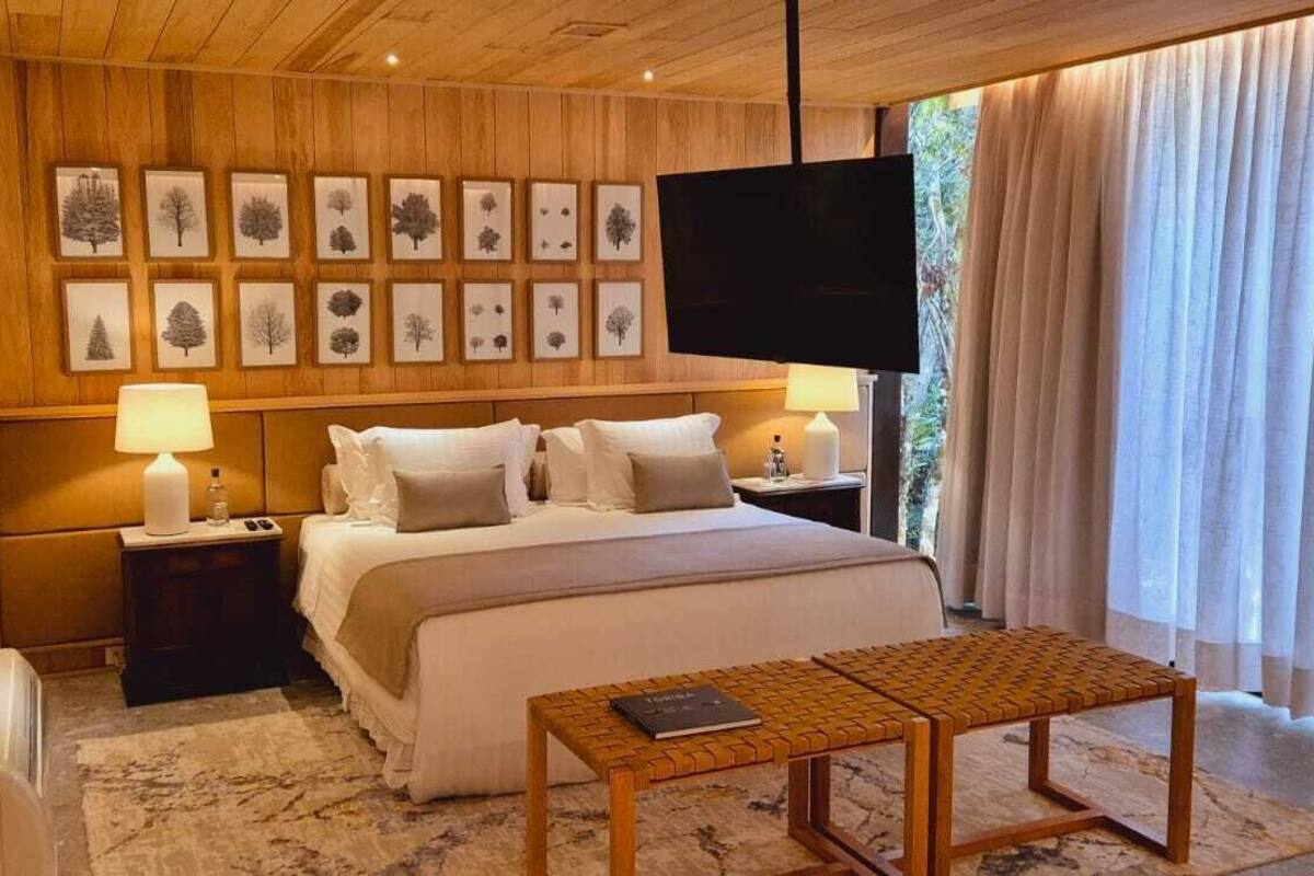 Une chambre à coucher comprenant un lit, des tables de chevet, un téléviseur à écran plat et des tableaux encadrés accrochés au mur.
