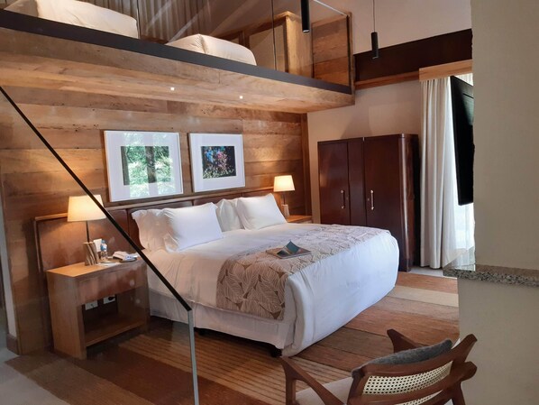 Una habitación de hotel con una cama, mesitas de noche, una silla, un armario y cuadros en la pared.