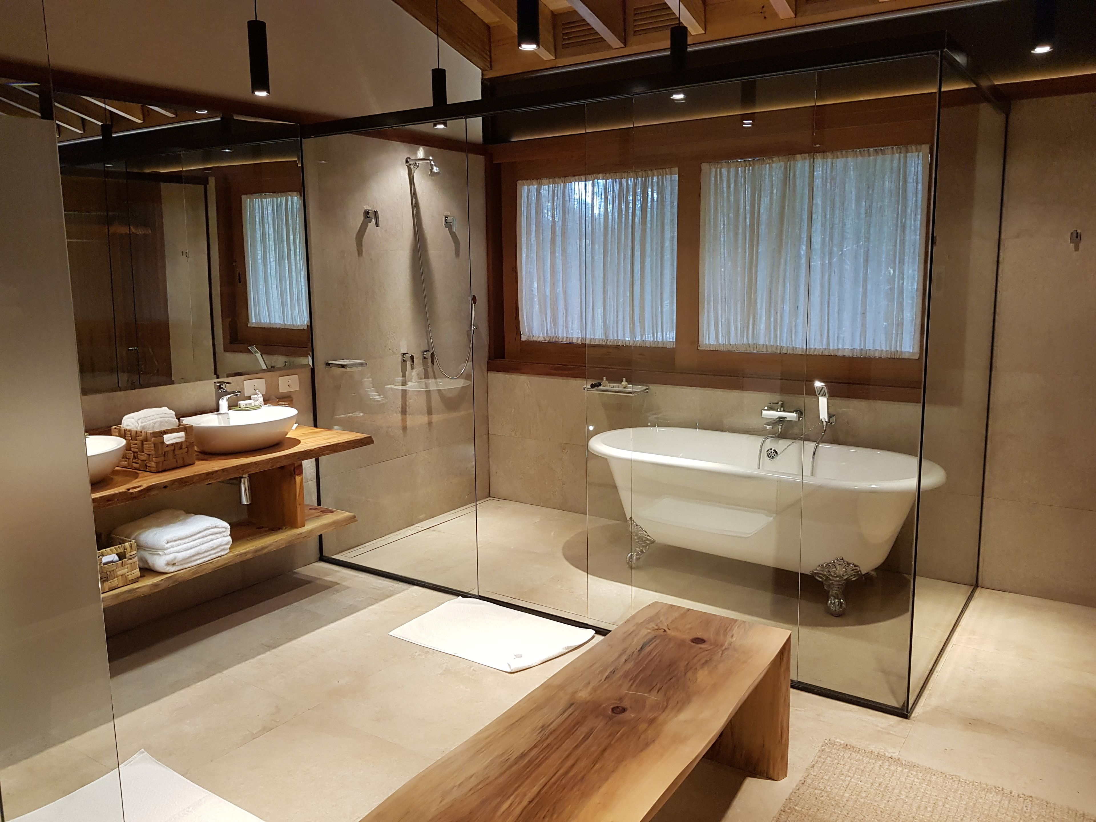 A modern bathroom with a glass-enclosed shower, a freestanding bathtub, and a wooden vanity with a bowl sink.